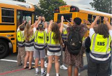  students welcoming others stepping off school bus